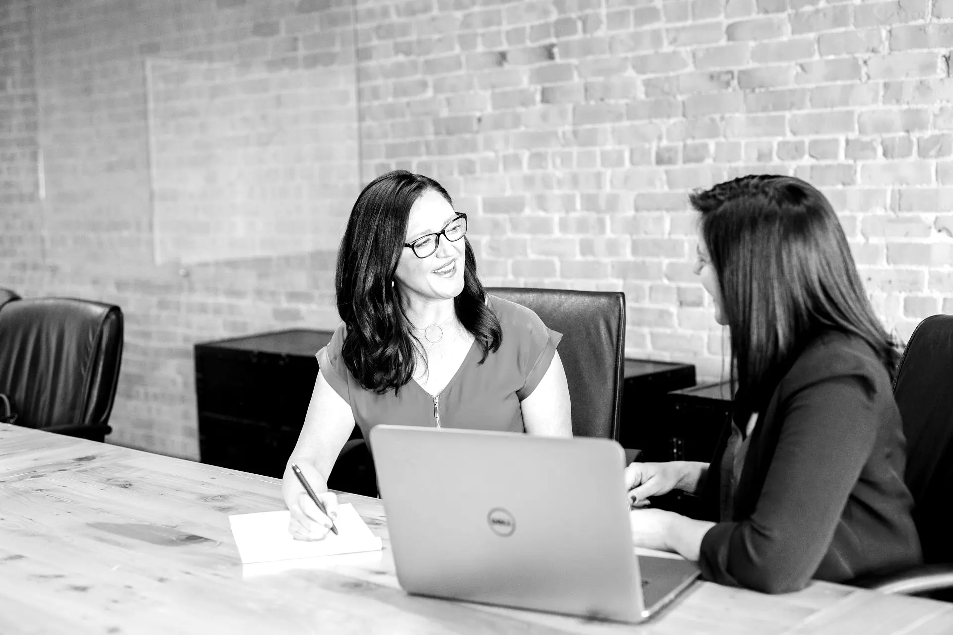 woman in teal t-shirt sitting beside woman in suit jacket