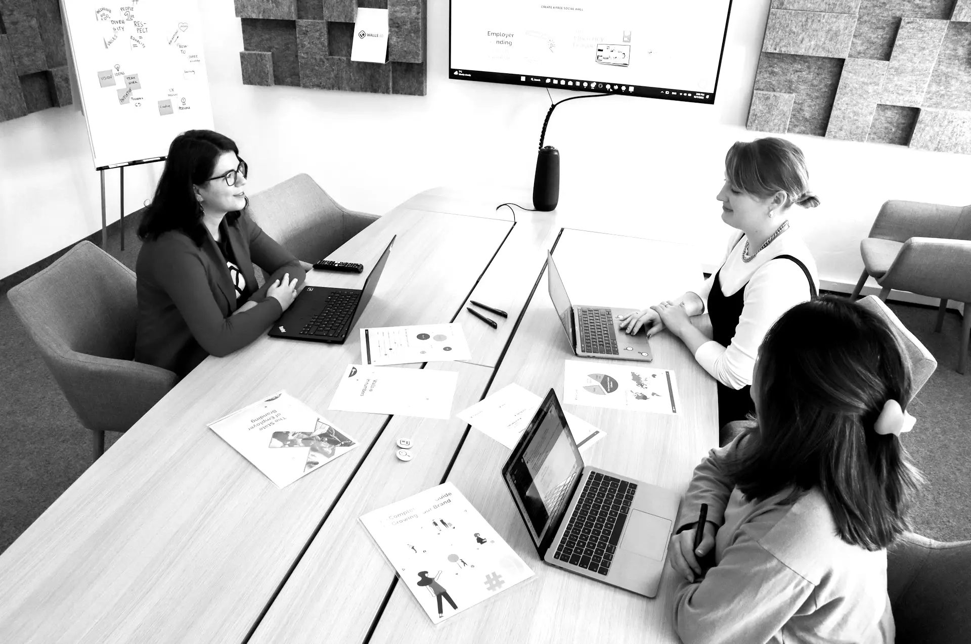 a group of people sitting around a table with laptops