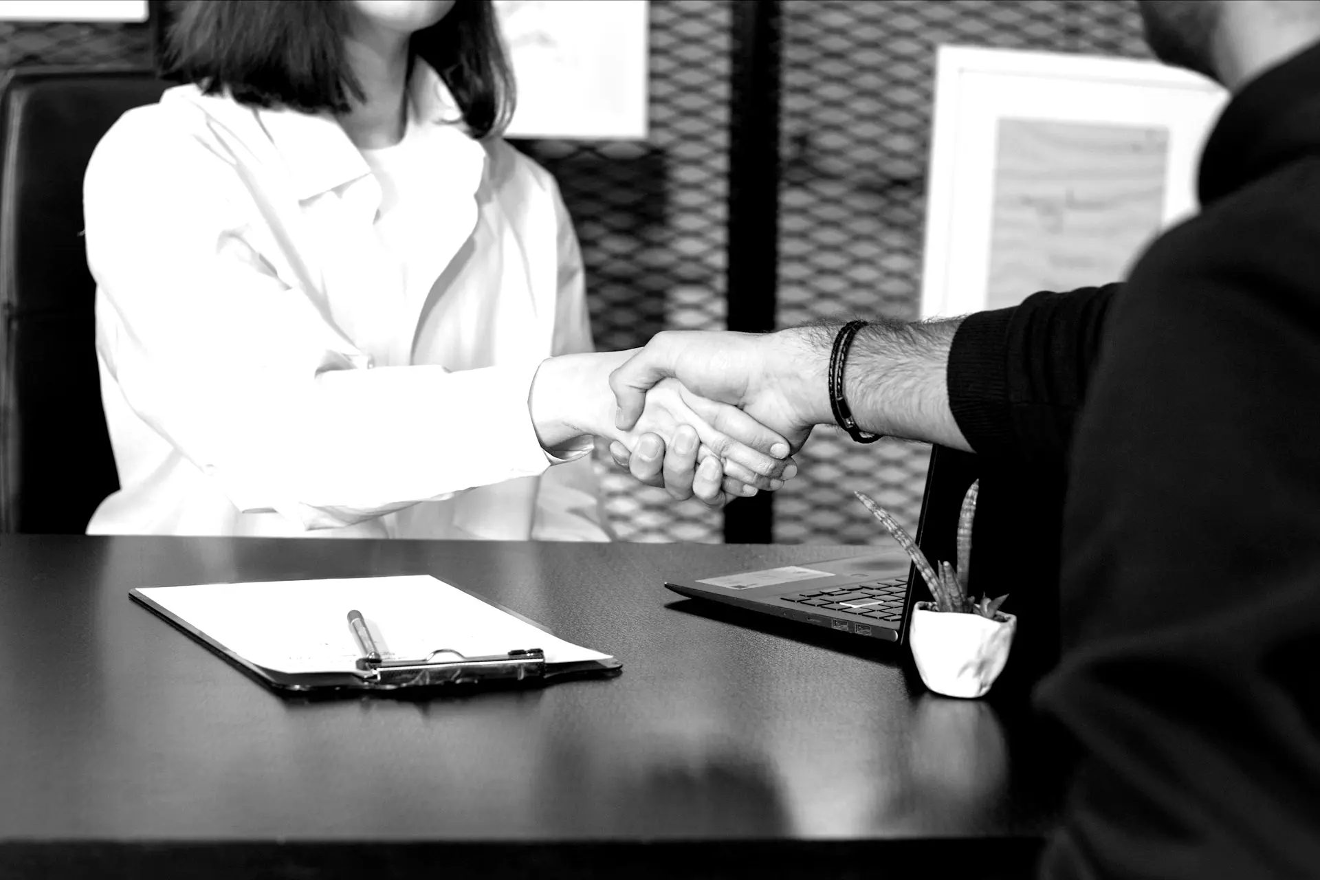 a man and a woman shaking hands in front of a laptop