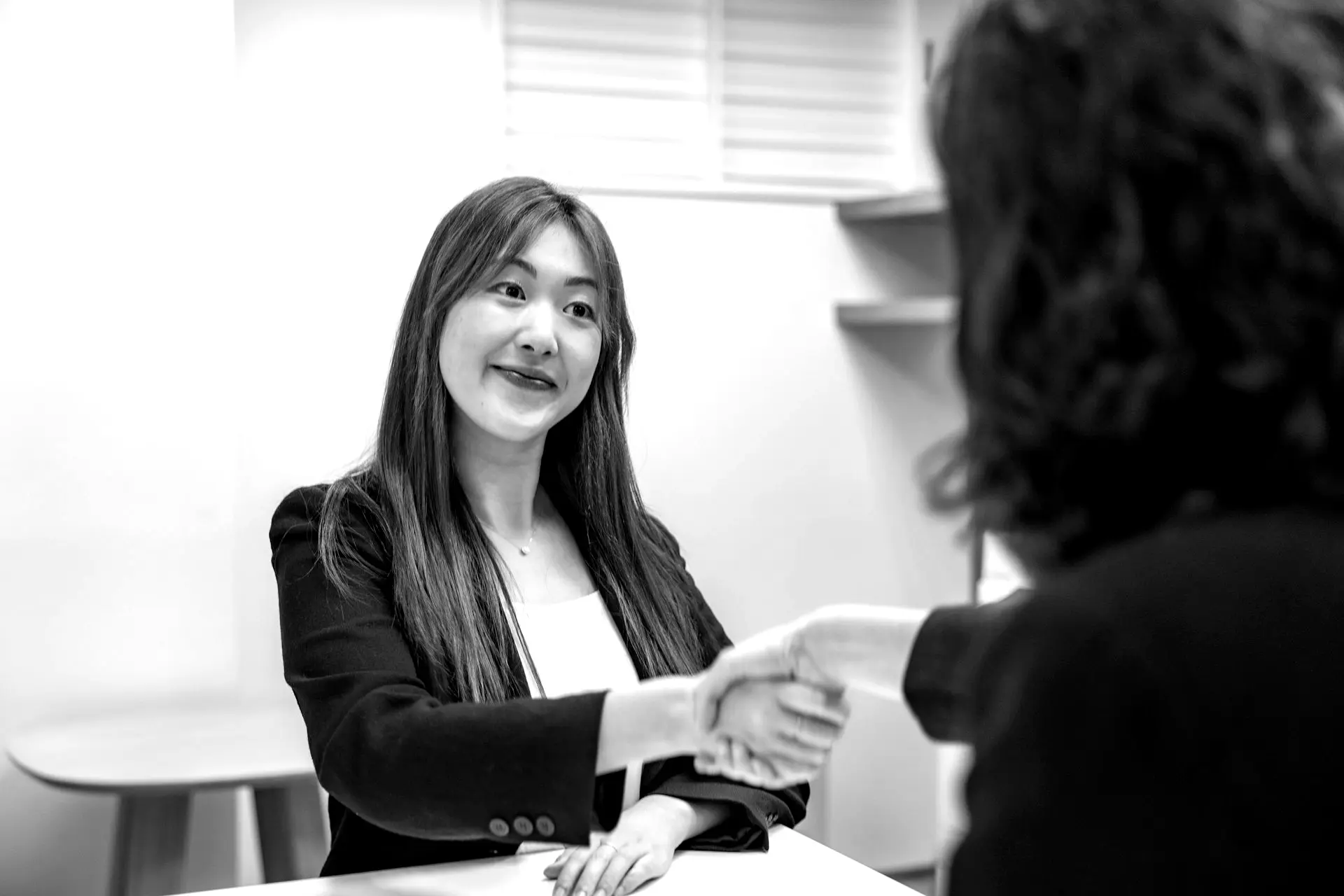 a woman shaking hands with another woman at a table
